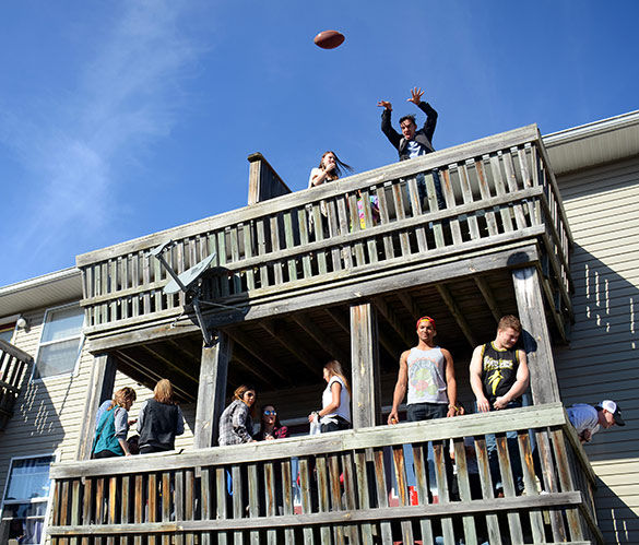 A Polar Bear participant tosses a football from a balcony to partiers below Jan. 30 on South Poplar Street. (DailyEgyptoan.com file photo)