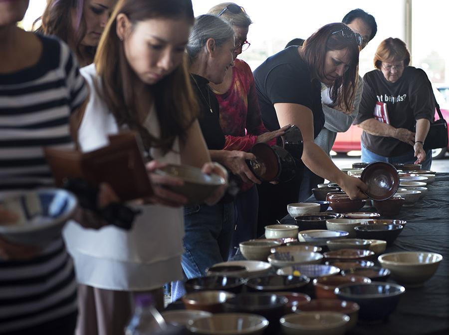 Attendees of the SIU School of Art and Design and Southern Clay Works' Empty Bowls fundraiser queue alongside a table filled with ceramic bowls Saturday, Oct. 15., 2016, outside The Neighborhood Co-op Grocery in Carbondale. (Morgan Timms | @Morgan_Timms)