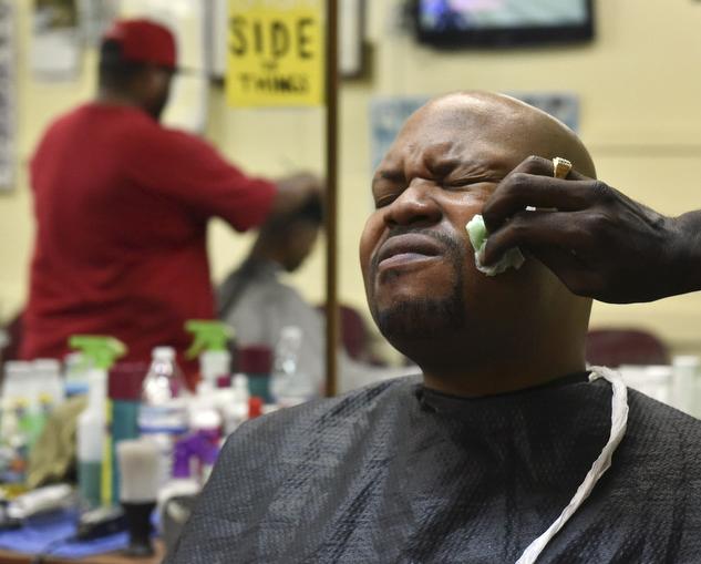 Taliq Montegomery grimaces as barber Terrence Upchurch rubs after shave on his face on Wednesday, Nov. 2, 2016, at Arnette’s barber shop. (Anna Spoerre | @annaspoerre)