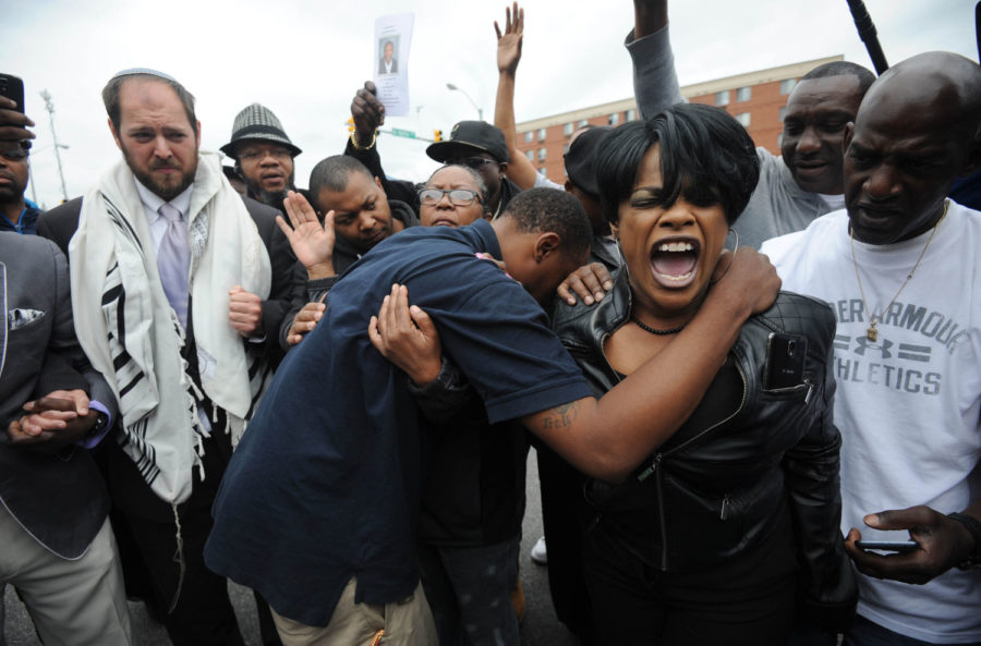Rev. Pamela Coleman, right, prays with Baltimore residents at the corner of West North Avenue and Pennsylvania Avenue on May 1 after charges were filed against six Baltimore police officers in the death of Freddie Gray in Baltimore, Md. (Kim Hairston/Baltimore Sun/TNS)
