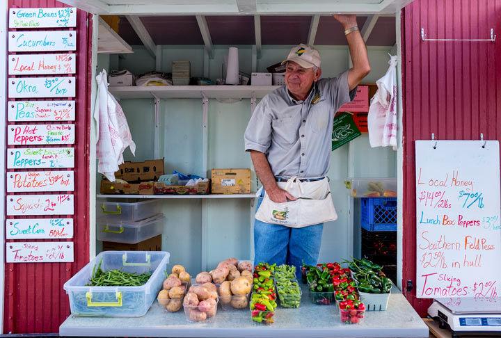 Homer Jenkins, of Murphysboro, smiles in his vegetable stand Wednesday at the Carbondale Community Farmers Market. After graduating from SIU, Jenkins raised hogs until three years ago when he opened his business Homer Grown. 