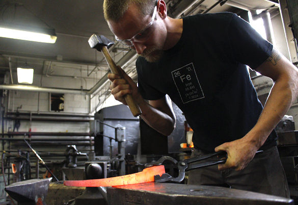 Dan Neville, a masters student studying metalsmithing from Detroit, Mich., forges steel with a hammer on Wednesday at L. Brent Kington Blacksmith shop in the Pulliam Industrial Wing.  “SIU is unique because it is the only school in the country that offers a MFA in metalsmithing,” Neville said. “The shop brings in people from all over the world wanting to study metalsmithing. When working with steel, you have to move quick so the steel does not cool and harden.”  Neville’s work will be on display at his MFA Thesis Exhibition taking place May 2 to May 6 at the SIU Surplus Gallery. — April 27, 2016, Carbondale, Ill.