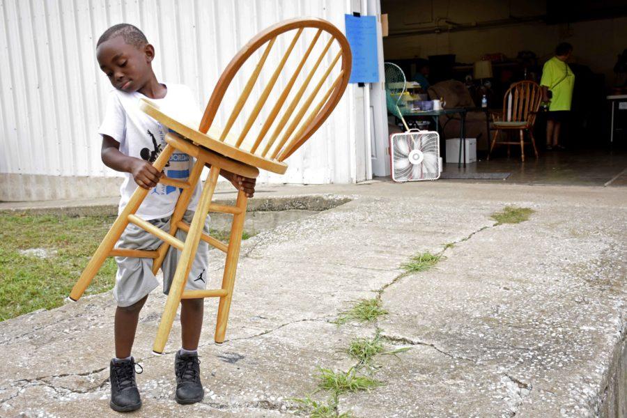 Titan Hills, 6, holds a chair at the Rotary Rotation Resale on Thursday, Aug. 18, 2016, in Carbondale. Hills carried the chair to assist his mother, Tanasha Rodgers. (Athena Chrysanthou | DailyEgyptian.com)