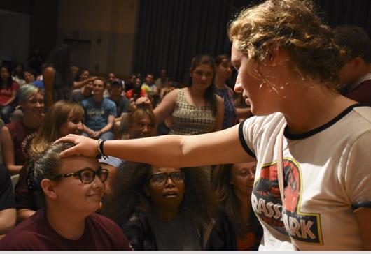 Margaret Lopez, a freshman from West Chester studying biological sciences, places her hand on sophomore Heather Duzan’s head while under hypnosis Friday, Aug. 26, 2016, during Chris Jones’ performance at the Student Center. Lopez said she thought the beginning of Jones’ performance was funny, but at the end she was confused and her memory was hazy. (Athena Chrysanthou | @Chrysant1Athena)