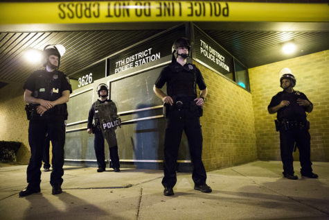 Police stand guard while protesters rally outside a police station the day after a fatal police involved shooting Sunday in Milwaukee, Wis. (Armando L. Sanchez/Chicago Tribune/TNS)