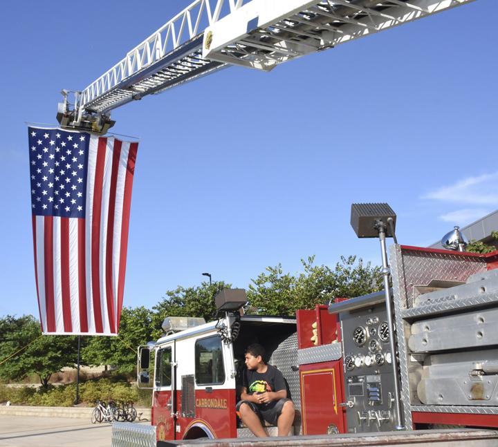 Jordyn Lomax-Brown, 10, sits on a Carbondale fire truck Saturday, Sept. 10, 2016, shortly after the start of the Saluki Kickoff 5K and Run to Remember 9/11 at Saluki Stadium. (Athena Chrysanthou | @Chrysant1Athena)