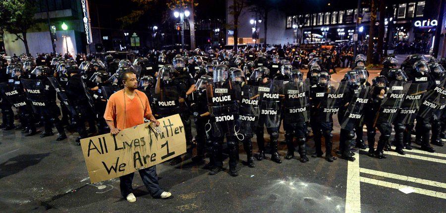 A+protestor+walks+in+front+of+Charlotte+officers+in+riot+gear+with+a+sign+reading+All+Lives+Matter+We+Are+1+in+Charlotte%2C+N.C.%2C+on+Wednesday%2C+Sept.+21%2C+2016.+The+protestors+were+rallying+against+the+fatal+shooting+of+Keith+Lamont+Scott+by+police+on+Tuesday+evening+in+the+University+City+area.+%28Jeff+Siner%2FCharlotte+Observer%2FTNS%29