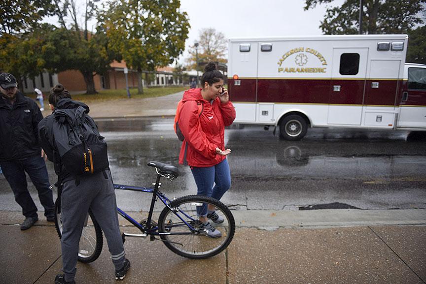 Liane Tatigian, a senior from Montreal, Canada, studying cinema and photography, talks on the phone with Trey Brainerd, graduate assistant for SIUs swimming and diving team, regarding a student who was stuck by a vehicle while riding a bike through a crosswalk Thursday, Oct. 20, 2016, outside the Communications Building in Carbondale. (Morgan Timms | @morgan_timms)