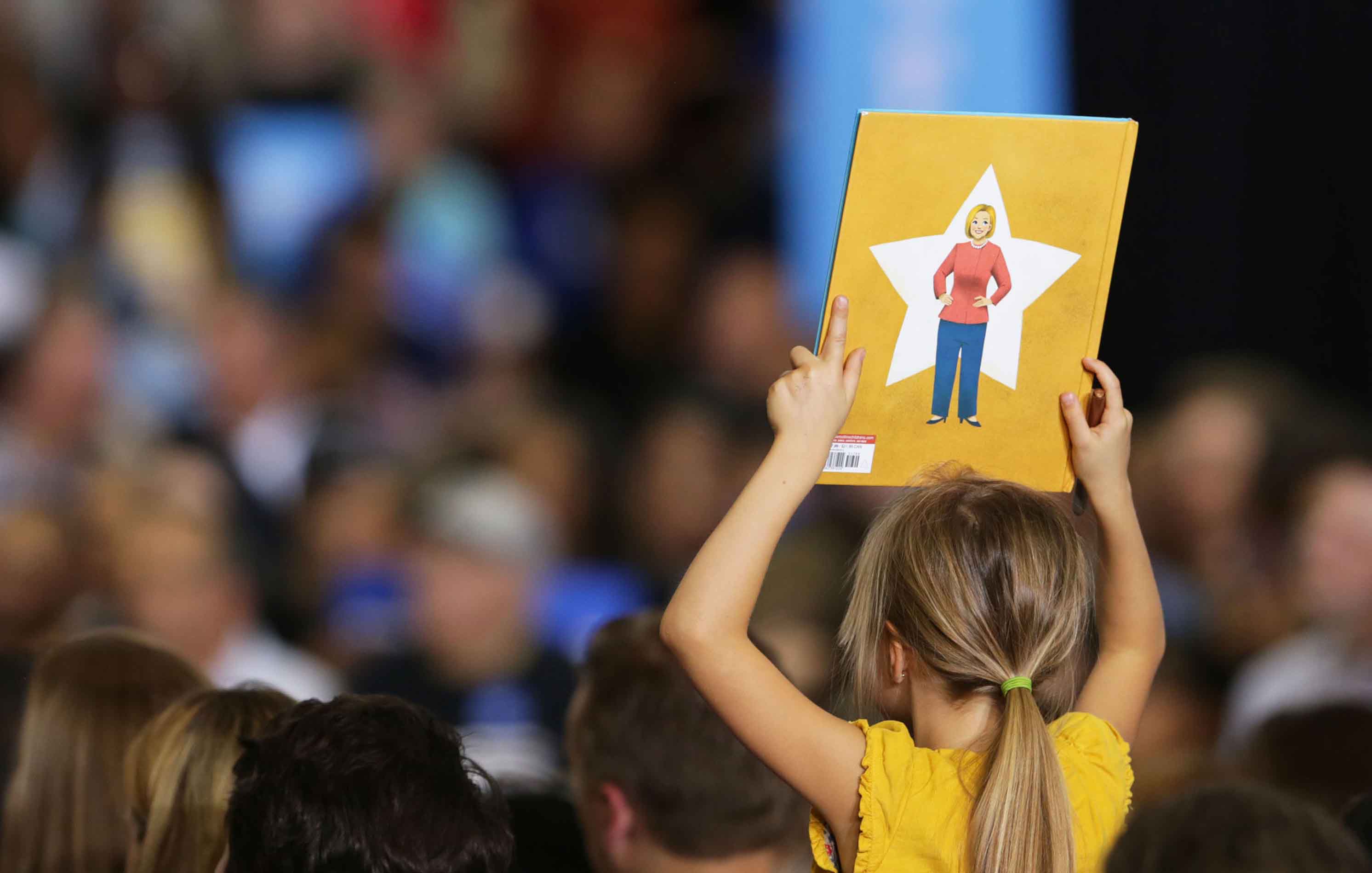 A young supporter of Democratic candidate Hillary Clinton holds up a book that has a drawing of Clinton on the back on the campus of Wayne State University at a voter registration event on Monday, Oct. 10, 2016 in Detroit, Michigan. Regina H. Boone/Detroit Free Press/TNS)