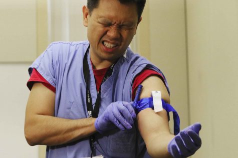 Dr. Tam Pham with UW Medicine and part of Dr. Eileen Bulger's trauma team, applies a tourniquet to himself — if it doesn't hurt, it's not properly applied. (Alan Berner/Seattle Times/TNS)