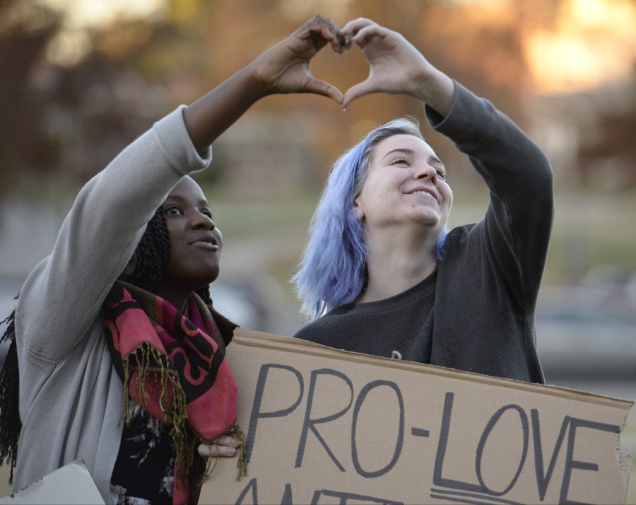 Oreoluwa Ojewuyi, left, and Brynn Kosmicki form a heart with their hands as they dance and sing to Love Is All You Need by the Beatles in front of Morris Library. The two were visiting the university campus Wednesday, Nov. 16, 2016, for a peaceful protest of the election of Donald Trump. (Bill Lukitsch | @lukitsbill)