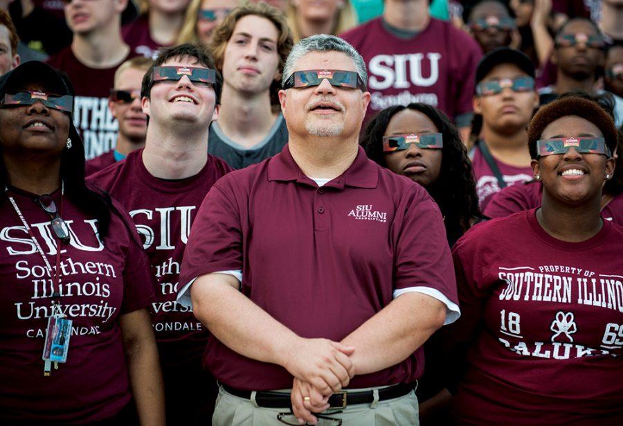 Surrounded by incoming freshman and new students, interim Chancellor Brad Colwell, center, wears a pair of solar eclipse glasses for a group photo following the convocation ceremony Friday, August 19, 2016, at SIU Arena. (Ryan Michalesko | DailyEgyptian.com)
