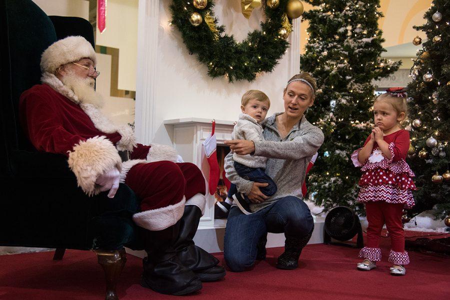 Callie James, of Carterville, attempts to persuade her children Gunnar James, 1, and Kinley James, 3, to sit with University Mall Santa, Max Luttrell, Wednesday, Nov. 30, 2016, in Carbondale. “They’re always terrified,” Callie said of her children taking pictures with Santa. “It’s an obligatory picture every year.”
This is Luttrell’s eighth year portraying Santa at University Mall where he will meet with guests until Christmas Eve. “[I want to do this] for the enjoyment of the kids and for the overall season to bring joy,” Luttrell said. “When you love to do something, it’s easy and it’s fun.” He said watching the kids’ reactions and smiles are some of his favorite aspects of the job.