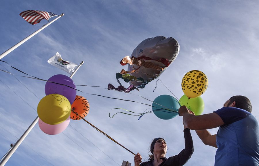 April Stanley, of Carbondale, helps Associate Professor of Cinema and Photography Antonio Martinez untangle balloon strings Saturday, Jan. 21, 2017, during the Southern Illinois Womens March in Carbondale. Stanley said the pair brought balloons to bring the light of optimism to the march. (Morgan Timms | @Morgan_Timms)