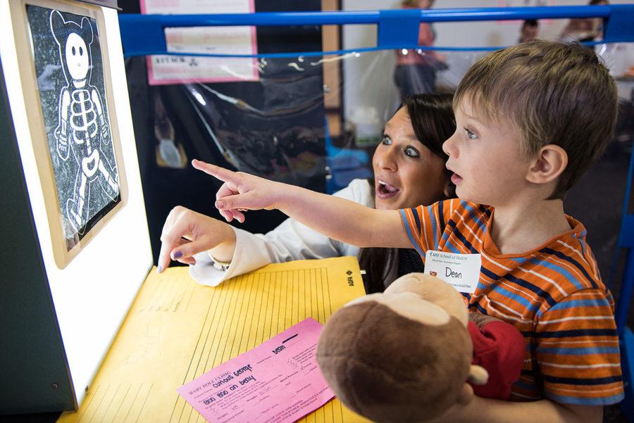 Dean, a student in SIU’s Head Start program, and Alexandra Spillman, a student in the physician assistant program from Effingham, look at an X-ray of Curious George during a doll clinic March 8, 2017, at the Head Start center in Carbondale. Adam Guss, a student in the physician assistant program from Milan, said the kids pretend their dolls are their own children when they come to the clinic. “It just brings kids to light about making them more comfortable coming into the doctor’s office,” Guss said. “Seeing their dolls, or babies as we call them, be more comfortable then it makes them more comfortable coming into see us.” This is the fifth year for the doll clinic. Head Start requested the last names, hometowns and ages of children not be published. (Jacob Wiegand | @jawiegandphoto) 