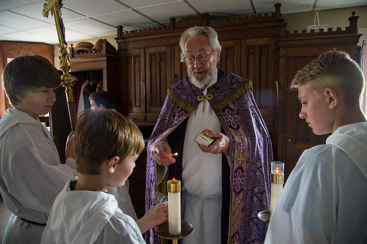 Monsignor Ken Schaefer lights the candle of Braden Burris, of Energy, while Johnston City resident Blake Gualdoni, with cross, and Gavin Shramm, of Herrin, observe prior to a Lenten ceremony of Stations of the Cross on Friday, March 24, 2017, at Our Lady of Mount Carmel in Herrin. Born in Belleville and raised in the St. Clair County village of Millstadt, Schaefer was ordained a priest on June 8, 1974. The priest has presided over the southern Illinois parish since 1994. (Jacob Wiegand | @jawiegandphoto)