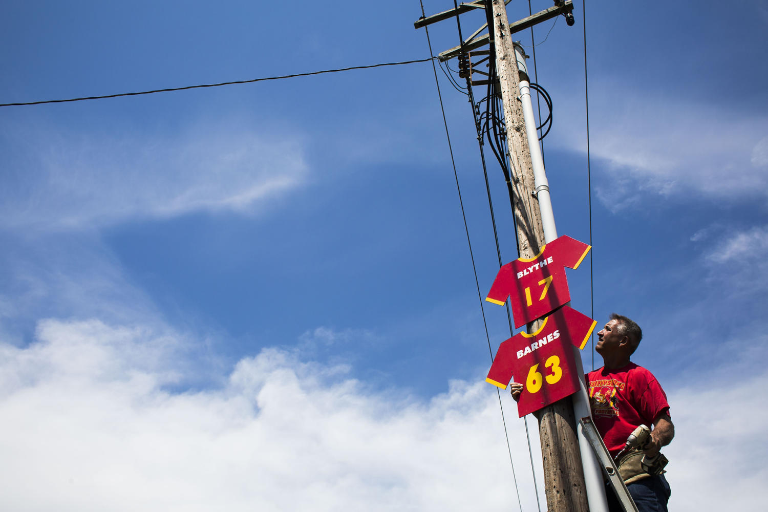 Mike Karg hangs Red Devils football jersey signs along North 14th Street prior to the 100th meeting between the Murphysboro Red Devils and the Carbondale Terriers on Friday, Aug. 25, 2017, in Murphysboro, Illinois. (Ryan Michalesko | @photosbylesko)