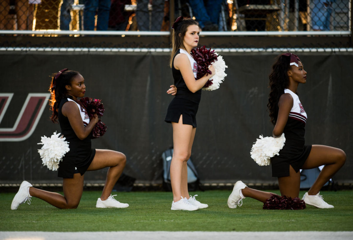 Sophomore radio, television and digital media major Czarina Tinker, of Nashville, Tennessee, left, and sophomore psychology major Ariahn Hunt, of Chicago, far right, kneel during the national anthem Saturday, Sept. 30, 2017, before the Salukis' matchup against the University of Northern Iowa Panthers at Saluki Stadium. President Donald Trump publicly criticized NFL athletes who kneel during the National Anthem to protest police brutality last week. (Brian Muñoz | @BrianMMunoz)