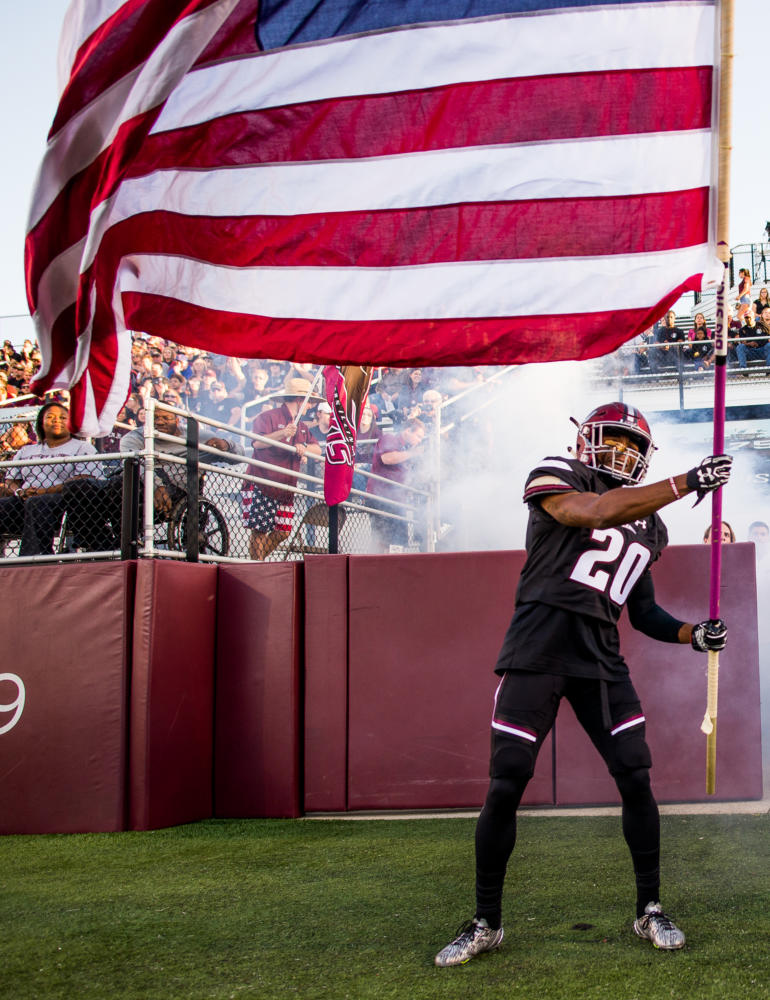 Junior wide receiver Jimmy Jones (20) waves the American flag Saturday, Sept. 30, 2017, as the Salukis rush into the stadium Saturday, Sept. 30, 2017 during the Salukis match up against University of Northern Iowa Panthers. The Salukis fell to the Panthers , 24 - 17. (Dylan Nelson | @Dylan_Nelson99)