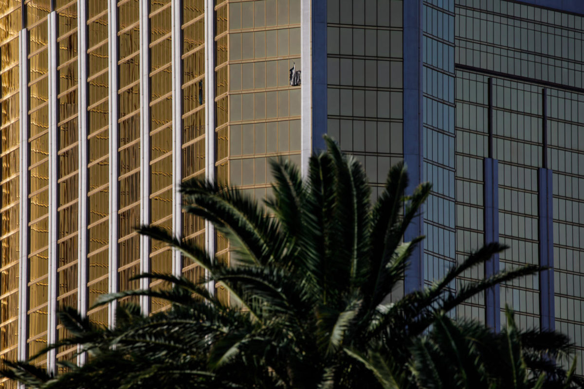 A curtain blows out of a broken window where a gunman opened fire from an upper story of Mandalay Bay resort on a country music festival across the street on the Las Vegas Strip on Sunday night, leaving at least 58 dead and more than 500 injured,  in Las Vegas, Nevada, on Oct. 2, 2017. (Marcus Yam/Los Angeles Times/TNS)