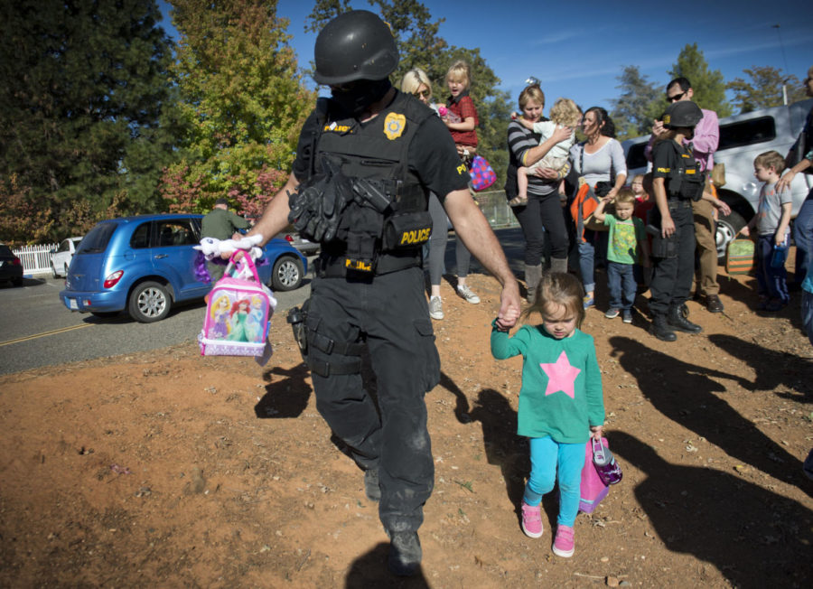 A special agent with the California Department of Justice walks a student from the Discovery Montessori school to her parents after being on lock-down because a suspect in the multiple shootings of officers in Sacramento and Placer County on Friday, Oct. 24, 2014. A suspect armed with a rifle left one Sacramento shefiffs deputy dead, a motorist gravely injured, and two Placer Conty sheriffs deputies wounded in a 30-mile crime spree. (Hector Amezcua/Sacramento Bee/MCT)