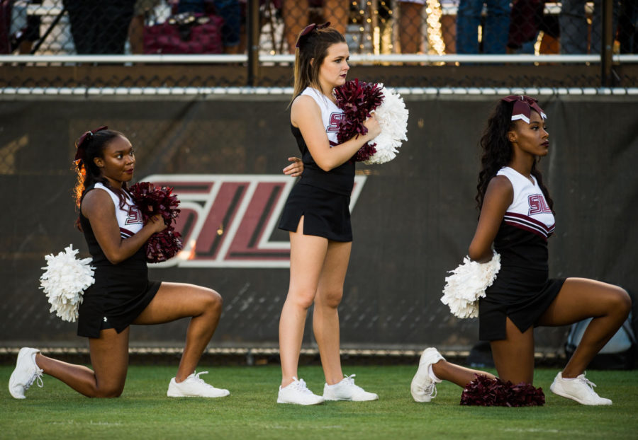 Sophomore psychology major Ariahn Hunt, left, and sophomore pre-med major Alaysia Brandy, both of Chiacgo, kneel during the national anthem Saturday, Sept. 30, 2017 before the Salukis matchup against the University of Northern Iowa Panthers  at Saluki Stadium. (Brian Muoz | @BrianMMunoz)