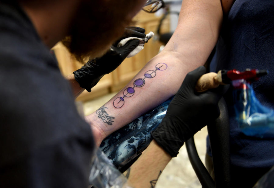 Johnny Davis, of Carbondale, gives a permanent reminder to Anne Millard, of Champaign, of the 2017 solar eclipse at Artistic Mind Tattoo and Body Piercing Saturday. I decided I dont want a little item that I can break, lose or you know, somebody is going to steal it, Millard said. So I thought Im going to get a tattoo for it [eclipse] so I can always remember it. (Athena Chrysanthou | @Chrysant1Athena)