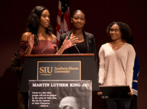 SIU cheerleaders Ariahn Hunt, Alasyia Brandy, both of Chicago, and Czarina Tinker, of Nashville, Tennessee, speak in front of a packed crowd Monday, Jan. 15, 2018, during the Carbondale NAACP Martin Luther King Jr. breakfast in the SIU Student Center. The girls were recognized for their willingness to protest police brutality by kneeling during the national anthem at sporting events. (Brian Muñoz | @BrianMMunoz)