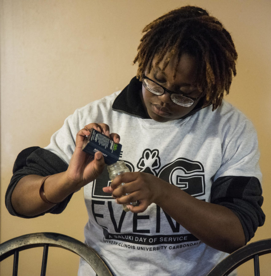 Rebekah Sanders, a senior studying criminal justice, from Belleville, refills a rosemary spice jar, Saturday, April 7, 2018, at the Carbondale Women’s Center as a volunteer site leader for The Big Event hosted by SIU. (Mary Newman | @MaryNewmanDE)