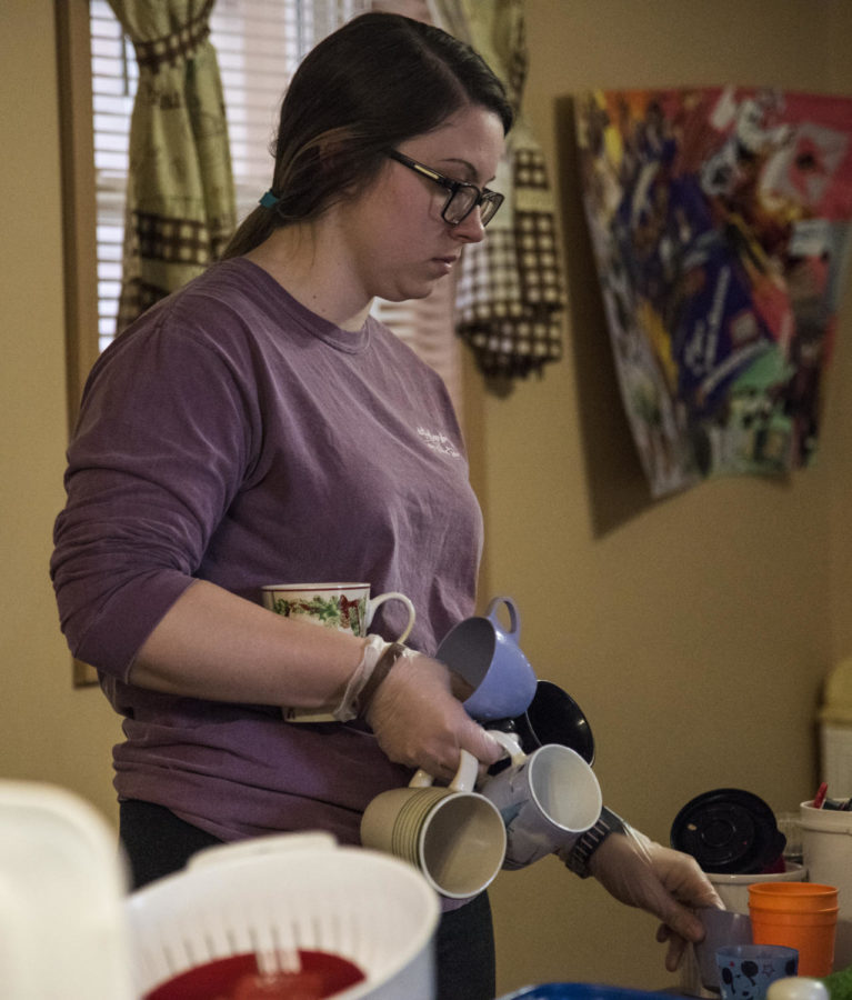 Savannah Idecker, a sophomore studying dental hygiene from New Athens, gathers dishes to put back in the kitchen, Saturday, April 7, 2018, at the Carbondale Women’s Center as a volunteer for SIU’s The Big Event. (Mary Newman | @MaryNewmanDE)