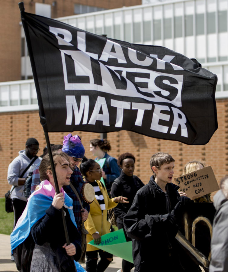 Michael Thornton, a sophomore from Naperville studying digital media arts and animation, carries a Black Lives Matter flag in front of the student center Thursday, April 5, 2018, during a protest on the proposed police academy at the Southern Illinois University Carbondale campus. (Brian Munoz | @BrianMMunoz)