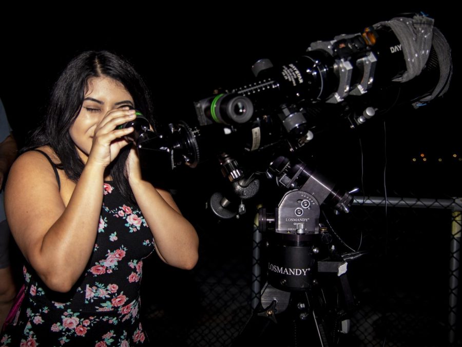 Jenifer Ruiz, a senior studying radiation therapy, of Zion looking at the planets and stars through a telescope on the roof of Neckers during the physic departments public astronomy viewing, Sunday, Aug. 2018. (Allie Tiller | @allietiller_de)