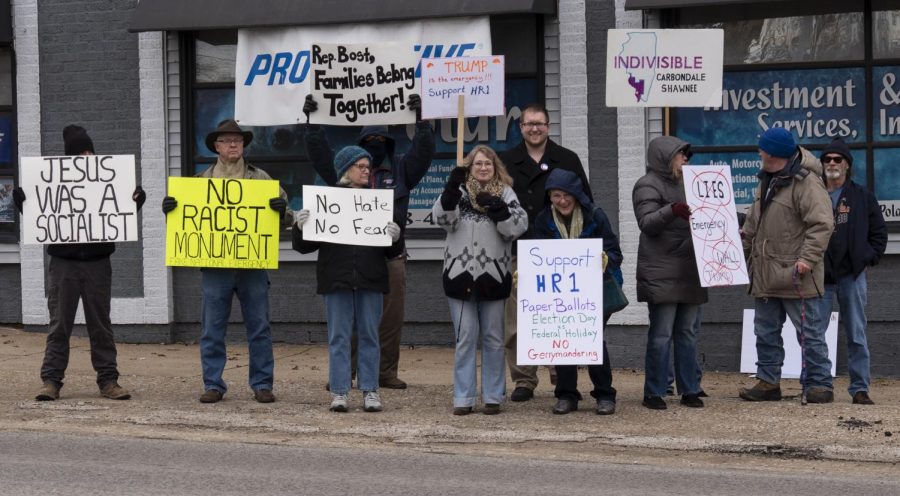 Protestors stand alongside Carbondale mayoral candidate Nathan Colombo on Monday, Feb. 18, 2019 outside Carbondale’s Hunter Building. The group protested President Donald Trumps recent declaration of a national emergency on the Mexican border.