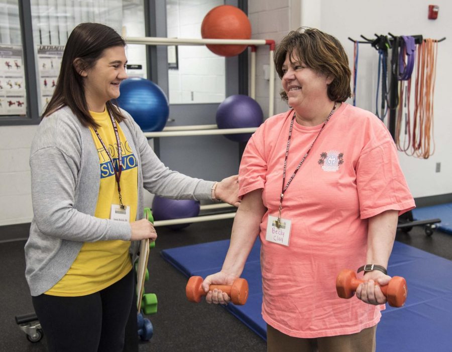Jamie Brolick assists Strong Survivor participant, Becky Clay, as she lifts weights in the Aerobics and Weight Training Center on Tuesday, Feb. 19, 2019 at John A. Logan. Brolick actively volunteers in the program in order to help cancer survivors regain their strength. 