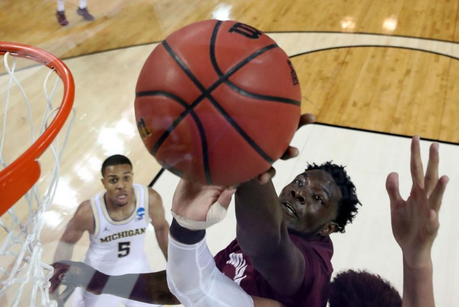 Jamar Akoh #15 of the Montana Grizzlies reaches for a rebound as Jaaron Simmons #5 of the Michigan Wolverines looks on during the first round of the NCAA Basketball Tournament at INTRUST Arena on March 15, 2018 in Wichita, Kansas. 