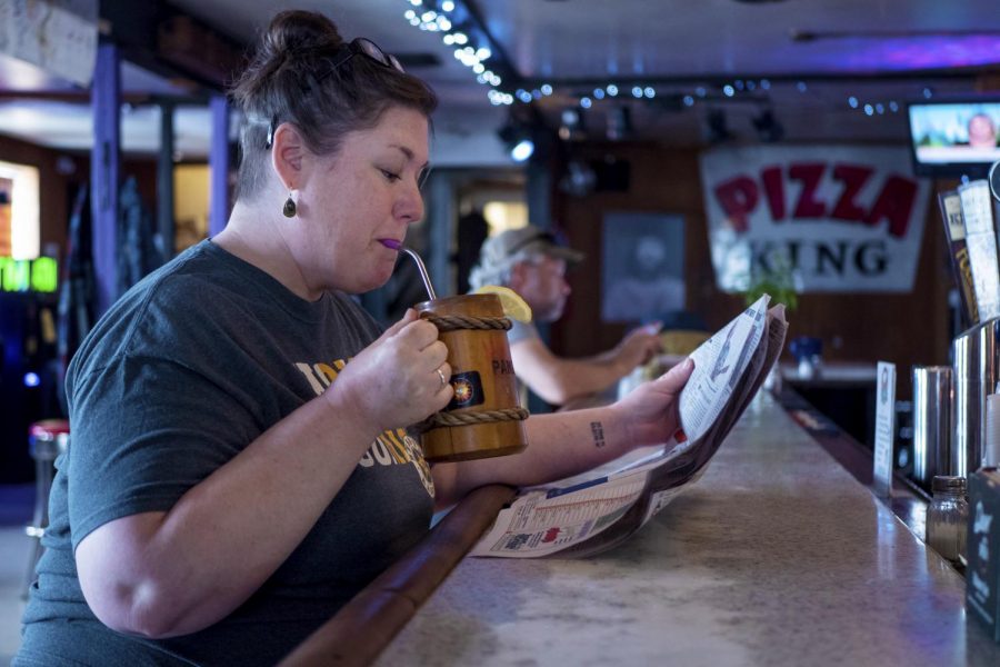 Lisa Pangburn-Fenton, of De Soto, sips her drink while she reads the newspaper on Tuesday, April 23, 2019, at PK’s in Carbondale. 