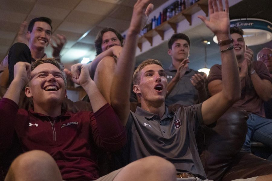 Seniors Peyton Wilhoit, of Searcy, Ariz., and Hunter York, of Decatur, react to their selection alongside the rest of the golf team on Wednesday, May 1, 2019, in Copper Dragon in Carbondale. York said, “It’s Louisville so it is convenient and close, its a great place [...] we’re super excited to get there and play in Nationals.” 