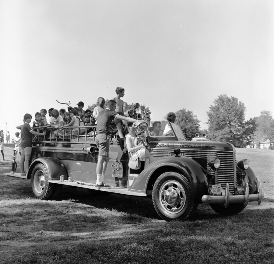 People in an old car, with the name Carbondale written on it, celebrating the Fourth of July. Photo courtesy of Morris Library Special Collections Research center, collection of “Neighboring Celebration,” from July 4, 1968. 