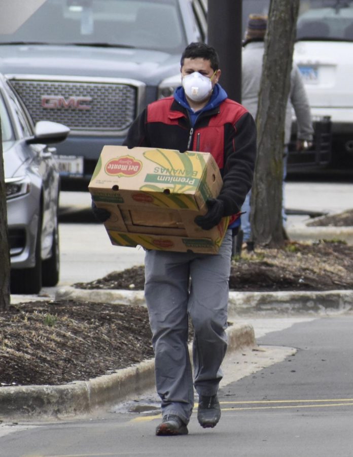 A man wearing a protective face mask carries the groceries he bought back to his pickup truck on March 20 in Niles, Illinois. Many hospitals across the country are experiencing a face mask shortage, forcing some healthcare professionals to reuse them.