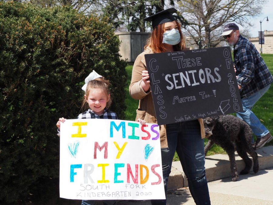 Jayden Brest, a senior at South Fork Senior High School, holds a sign next to her sister, who is in kindergarten, at the Gridlock Springfield protest at the capitol building in Springfield, Illinois on April 19, 2020.