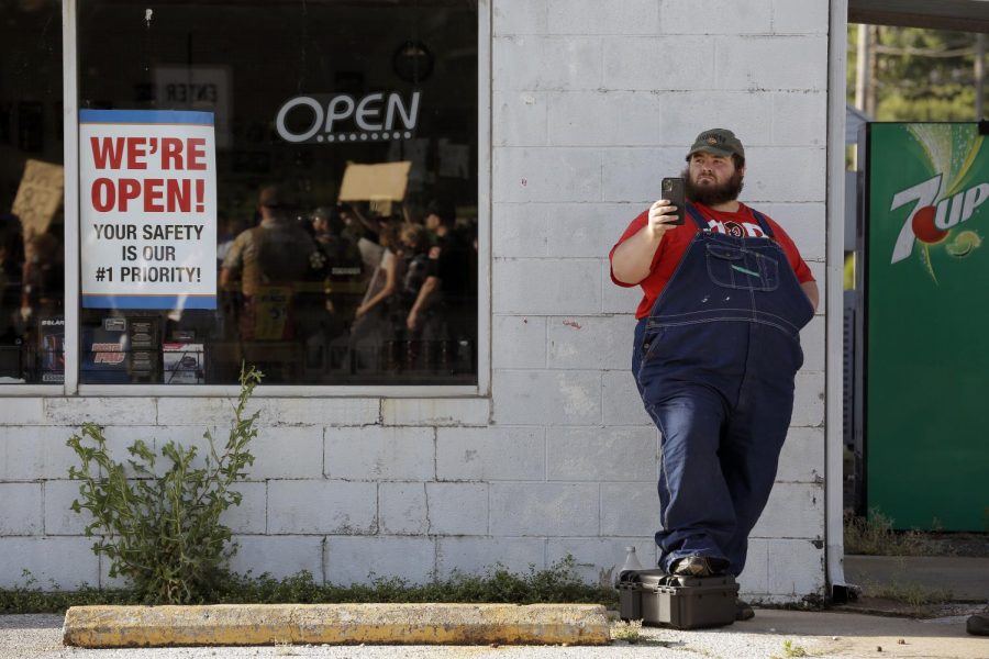A local resident uses his cell phone to record Black Lives Matter demonstrators as they march along Main Street, Anna, Illinois, Thursday, June 4, 2020.
