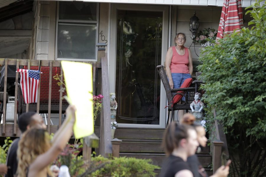 A local resident watches from her front porch as a group of Black Lives Matter demonstrators march past her home in the town of Anna, Illinois, Thursday, June 4, 2020.

