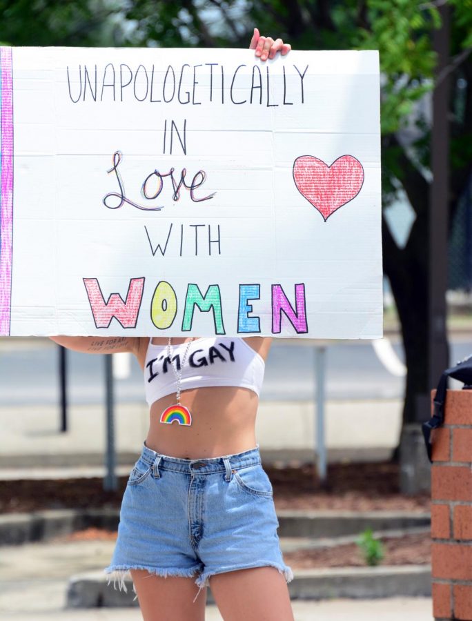 Sydney Browning, raises her sign to cars passing by on Main Street during Pride, June 28, 2020, Carbondale, ILL.