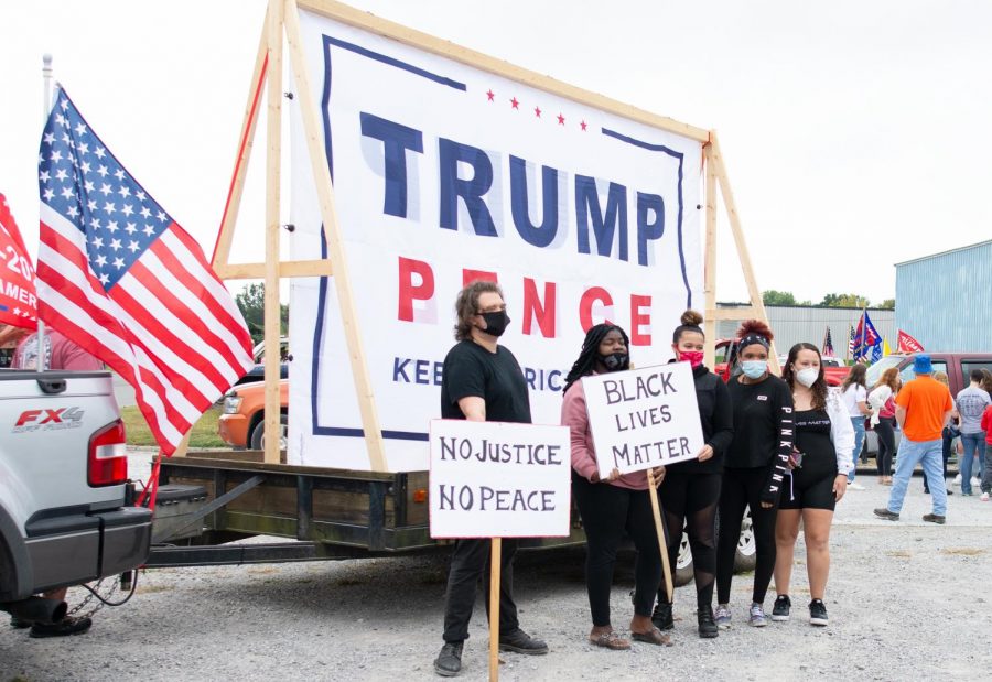 Black Lives Matter protesters pose for a photo in front of a Trump banner during the Trump Train on Saturday, Oct. 10, 2020, in Anna, Ill. “I was at the gas station not too long ago, it was after the Anna protest here, and somebody yelled out the ‘N word’ through the window. I always have racist experiences here,” Jessica Moore, fourth from left, said.