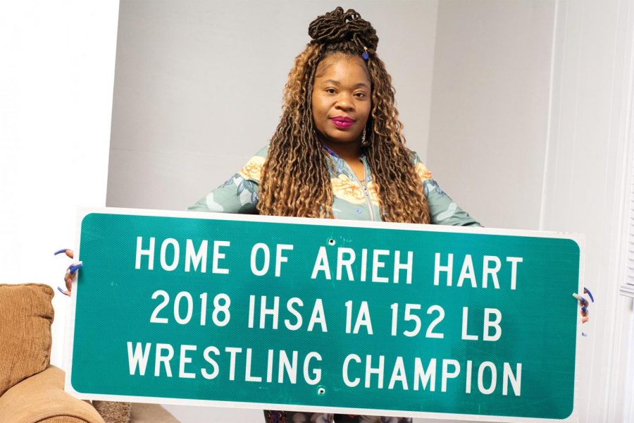 Easter Smith, holds a sign made for Arieh Hart for winning first place in the 2018 Wrestling State Championship. The sign was displayed in Anna back in 2018 as Hart was the first in the town’s
history to win first place in a state championship in wrestling. Smith, a mother of six and three being wrestlers, said she likes wrestling as it is a one on one sports so it teaches her children that even if you lose, you are still okay; as in wrestling there are matches one after the other and there is no time to process a loss. “It taught them a lot of discipline, a lot of self-control, a lot humbling,
[you] look yourself in the mirror and realize that you can’t blame anyone else,” Easter said. That
is what made her fall in love with wrestling.