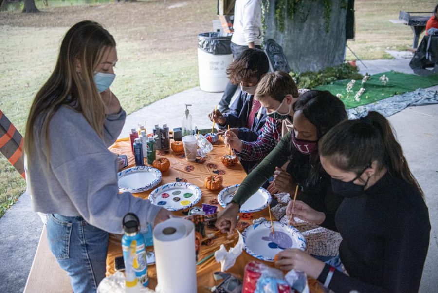 Grace Durocher, a biochemistry major, helps out fellow students paint pumpkins at the Moon Light on the Lake event Saturday, Oct. 17, 2020, near campus lake. This was just a good way to get people out, because of Coronavirus, all these students have been stuck in their dorms with nothing to do. So we wanted to offer a safe setting for people to get out, below off some stress, meet some new friends, and just have a good night, Durocher said. 