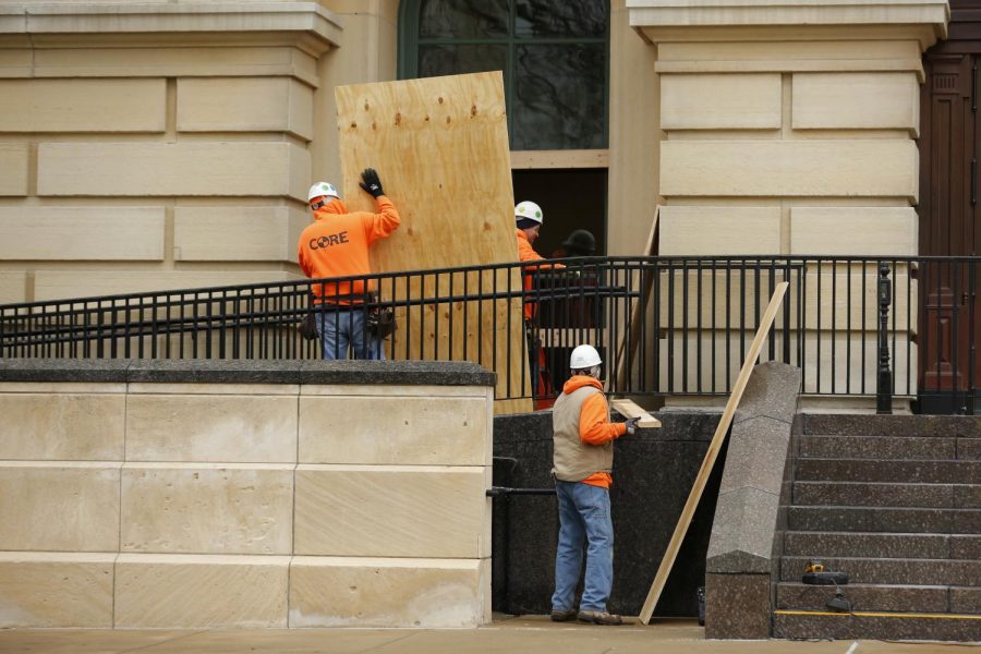 Workers board up windows at the Illinois State Capitol building on Saturday in Springfield in preparation for anticipated violence leading up to Biden’s inauguration.  The FBI released a memo recently to law enforcement agencies across the country warning about potential violent protests at all 50 state capitols after the deadly mob attack on the U.S. Capitol last week.