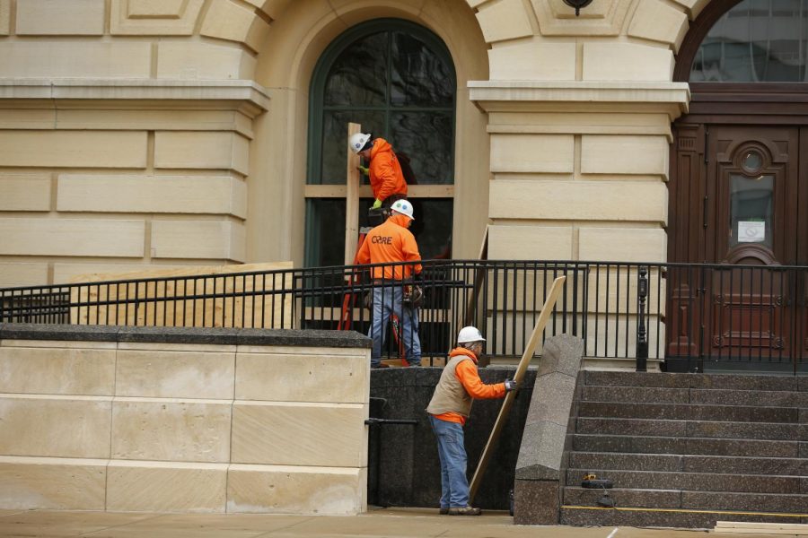 Workers board up windows at the Illinois State Capitol building on Saturday in Springfield in preparation for anticipated violence leading up to Biden’s inauguration.  The FBI released a memo recently to law enforcement agencies across the country warning about potential violent protests at all 50 state capitols after the deadly mob attack on the U.S. Capitol last week.