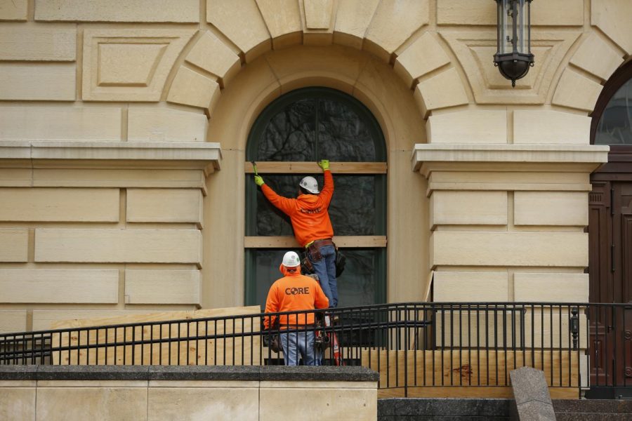 Workers board up windows at the Illinois State Capitol building on Saturday in Springfield in preparation for anticipated violence leading up to Biden’s inauguration.  The FBI released a memo recently to law enforcement agencies across the country warning about potential violent protests at all 50 state capitols after the deadly mob attack on the U.S. Capitol last week.