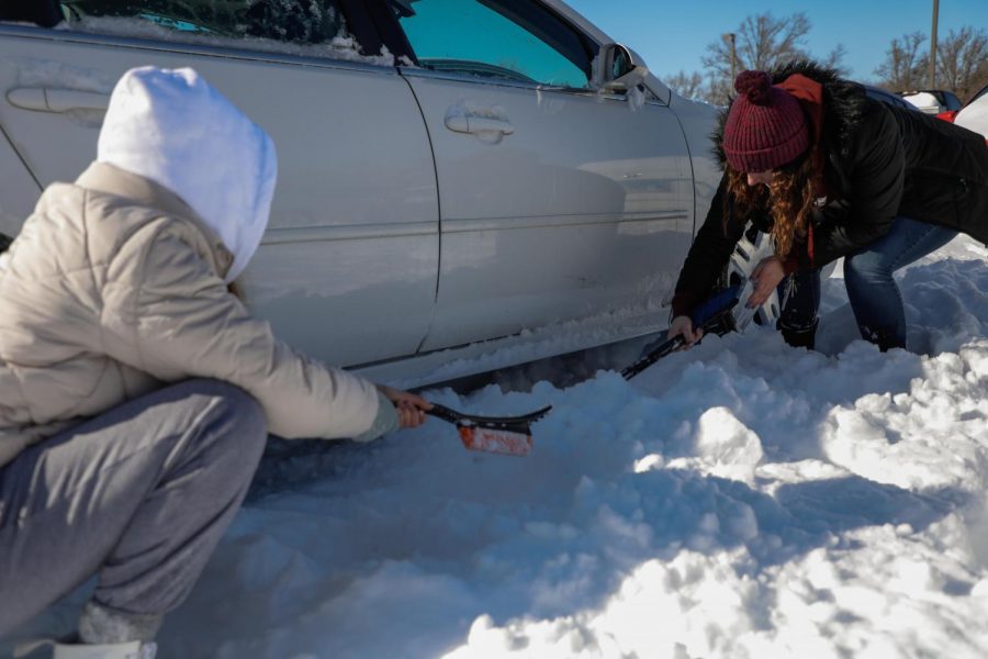 SIU freshmen, Molly Lindsey, and Mackenzie Ebmeyer scrape the snow away from their stuck car on Feb. 16, 2021. “It won’t go, either way, it’s very stuck,” said Ebmeyer in the West Campus parking lot.